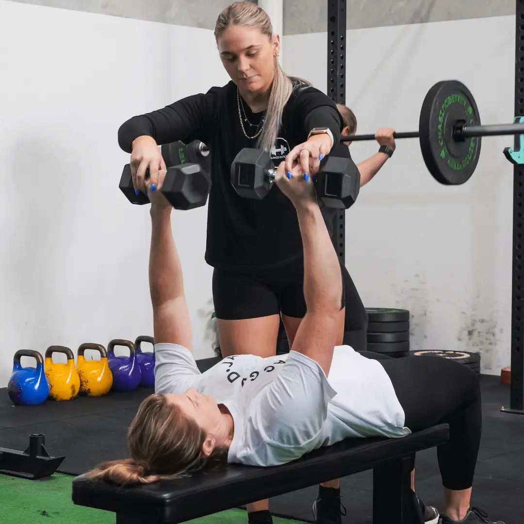 A personal trainer paying close attention to her personal training clients technique