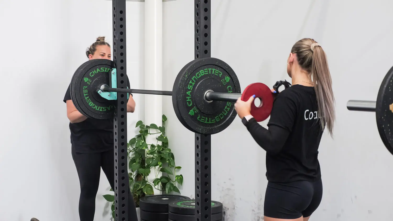 A coach helping a small group class member adjust their weights, and having a laugh