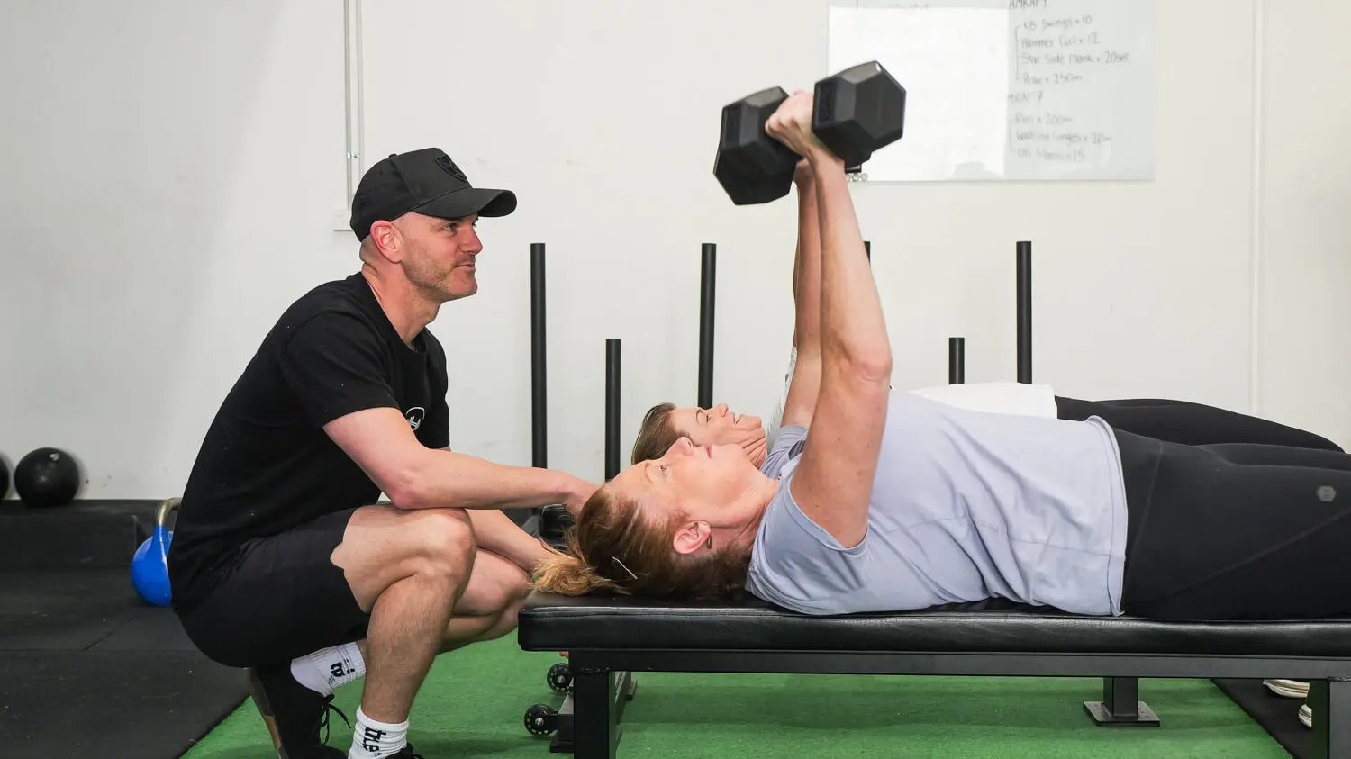 Coach taking a personal training client through a strength workout